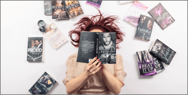Autorin liegend ließt in Buch Samantha J. Green umgeben von ihren Büchern, während sie Secrets of green Eyes liest